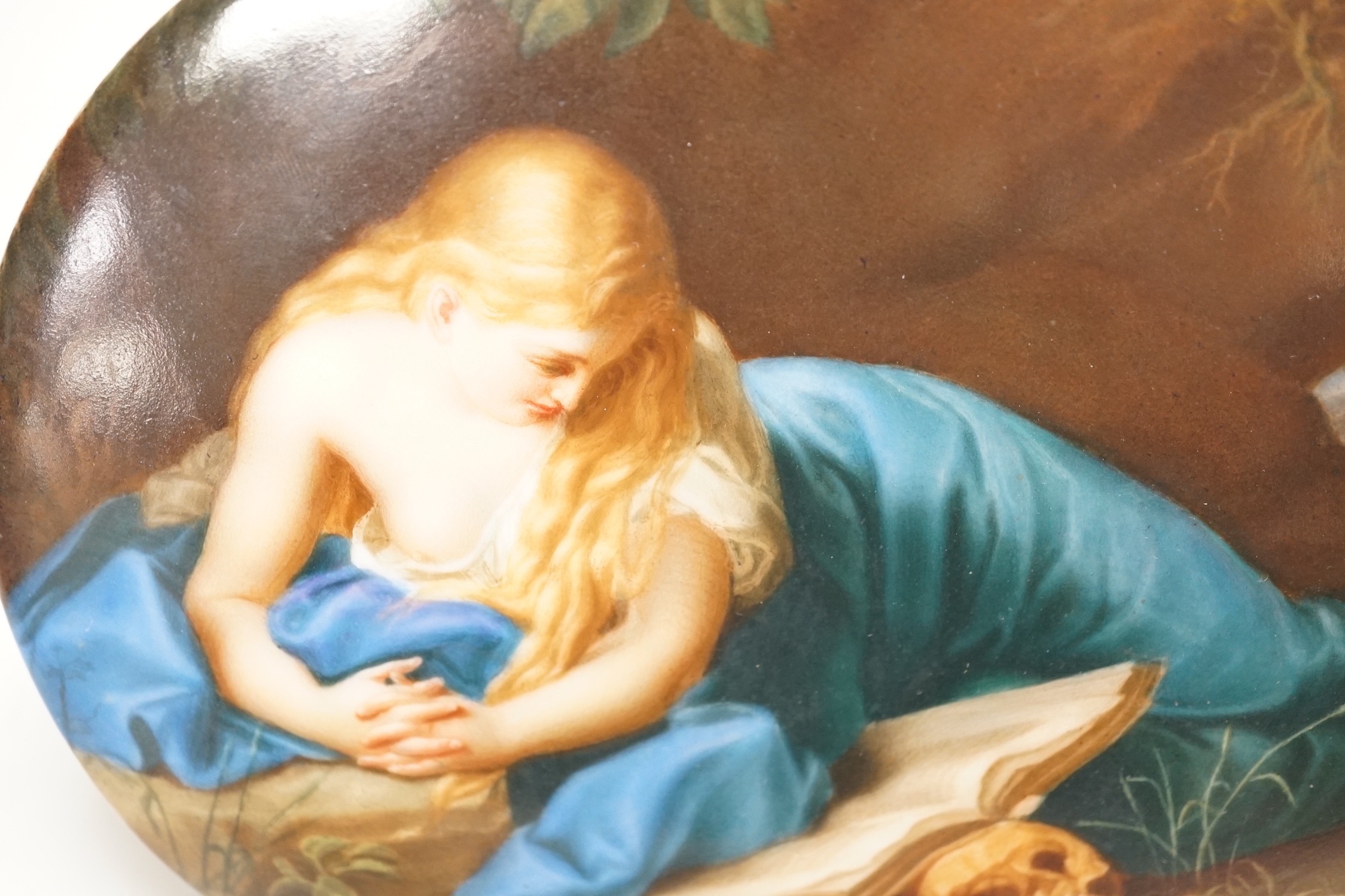A 19th century painted porcelain oval plaque of a reclining lady reading a book. The reverse stamped L. Sturm Dresden. 15x19.5cm
